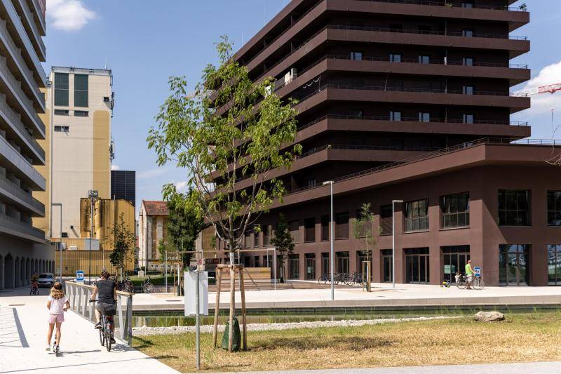 Eine Frau mit Kind im Vordergrund vor dem Gebäude