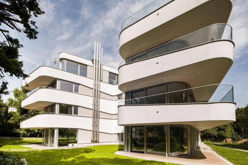 Diese Aufnahme ist direkt an einem Gebäude Ende des U-Förmigen Baus gemacht. Vom Garten wird nach oben fotografiert, sodass die Balkone am Eck wie ein Pfeil ins Bild zeigen. Der weiße Bau zeigt einen deutlichen Kontrast zum Grün darum. Diese Aufnahme ist direkt an einem Gebäude Ende des U-Förmigen Baus gemacht. Vom Garten wird nach oben fotografiert, sodass die Balkone am Eck wie ein Pfeil ins Bild zeigen. Der weiße Bau zeigt einen deutlichen Kontrast zum Grün darum.