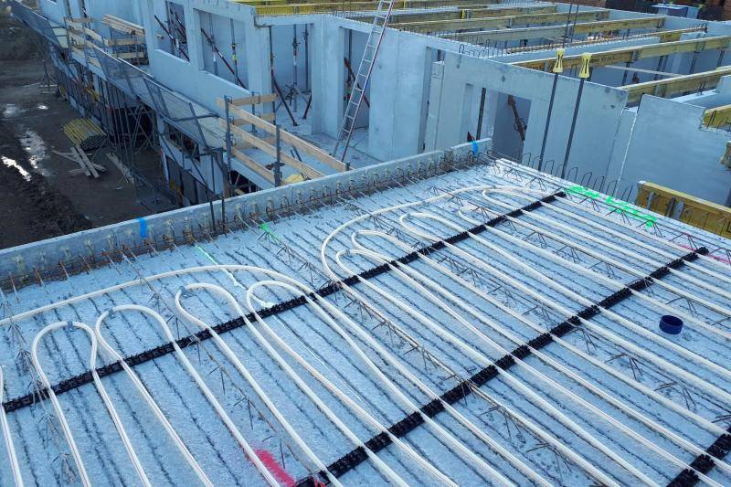 Zu sehen sind Schlauchleitungen, die in die Beton-Schalung eingelegt sind. Foto aus der Bauphase. Im Hintergrund sind die Rohbauwände aus Beton zu sehen Zu sehen sind Schlauchleitungen, die in die Beton-Schalung eingelegt sind. Foto aus der Bauphase. Im Hintergrund sind die Rohbauwände aus Beton zu sehen