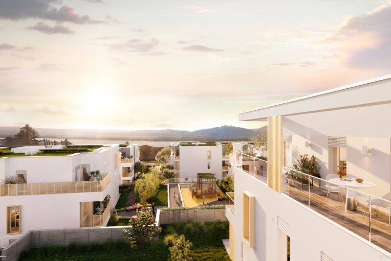 Blick in den Sonnenuntergang über die Dächer der Siedlung hinweg. Auf den Gebäudensind begrünte Flachdächer.