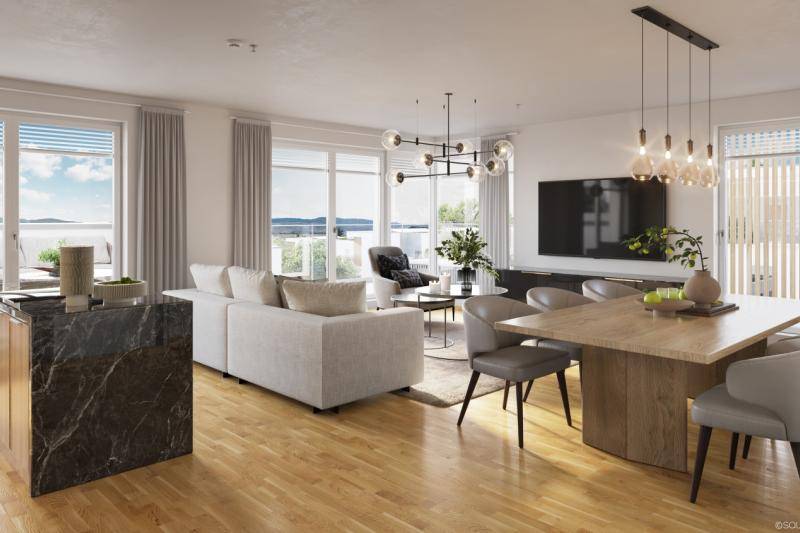 Ein Wohnzimmer mit Kücheninsel mit Marmor-Oberfläche. Dahinter ist eine weiße Couch. Der TV hängt an der Wand. Daneben ist der Estisch aus Holz mit 6 Sesseln. Der Boden aus hellem Parkett.