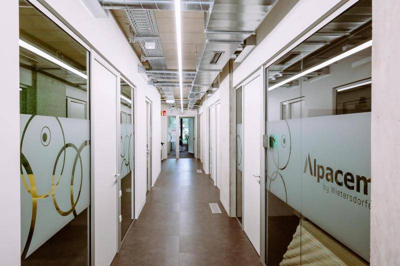 Enger Gang, an dem links und rechts Glaswände zu den Bürorämen sind.