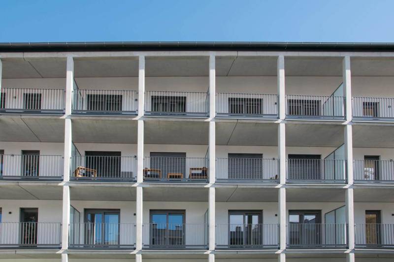 Drei Geschosse mit Balkonen und Metallgeländern. Betonstützen unterteilen Diese. Drei Geschosse mit Balkonen und Metallgeländern. Betonstützen unterteilen Diese.