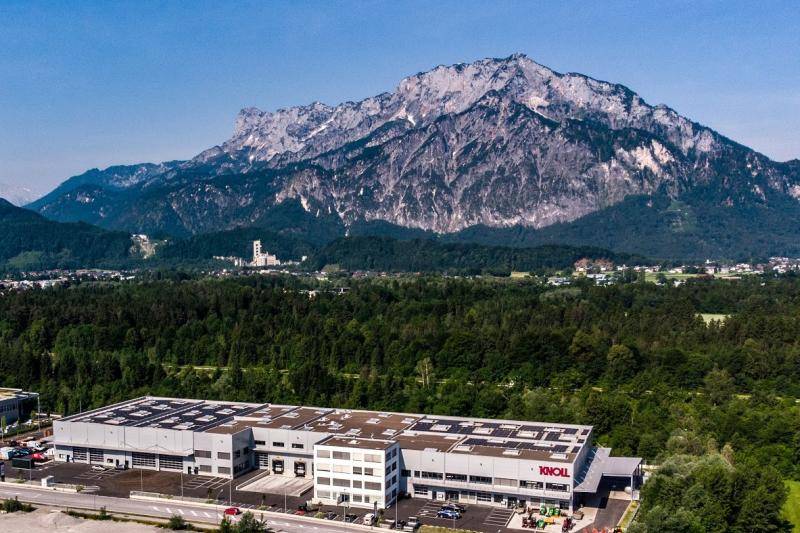 Im Hintergrund der Lagerhalle ist ein kleiner Wald zu sehen. Dahinter ein großer Berg. Das Gebäude ist umgeben von Grün, Im Hintergrund der Lagerhalle ist ein kleiner Wald zu sehen. Dahinter ein großer Berg. Das Gebäude ist umgeben von Grün,