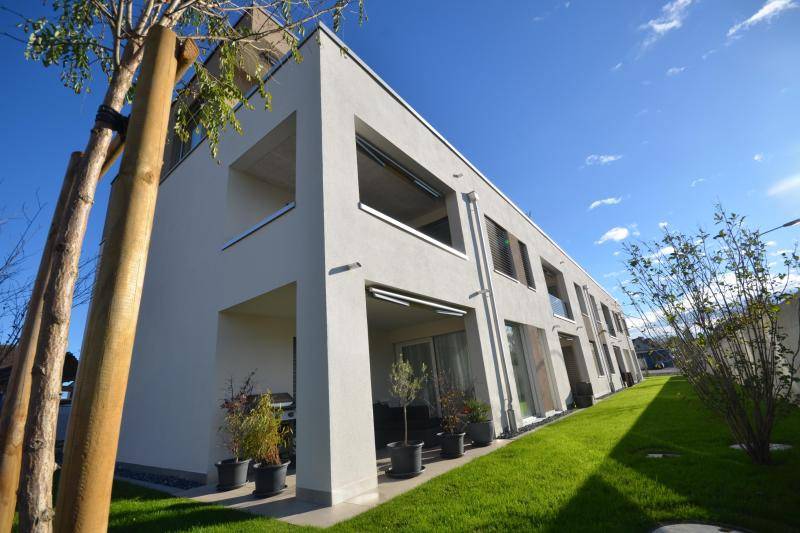 Loggien und Terrassen sind übereinander, jeweils an der Ecke des Hauses, angeordnet.. Das Gebäude ist von grünem Rasen umgeben.