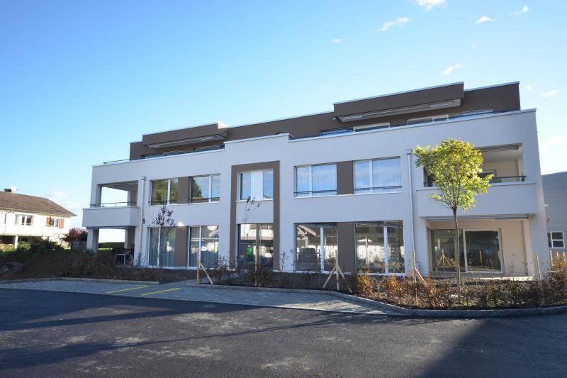 Vor dem Haus wird noch der Garten angelegt. Ein kleiner Baum wurde bereits gesetzt. Davor befinden sich zwei Parkplätze.