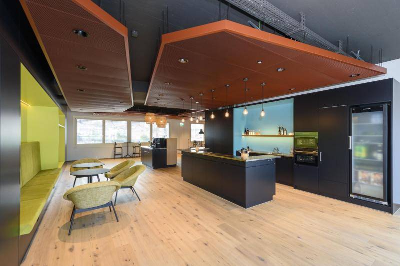 Hier seiht man eine Teeküche/Küche. Die Grundausstattung ist schwarz. Nieschen in den Wänden sind aber mit unterschiedlichen farben ausgestattet. Z.B. helles Blau und Grün. An der Decke hängen rote Elemene. Der Boden ist mit hellem Holz belegt. Hier seiht man eine Teeküche/Küche. Die Grundausstattung ist schwarz. Nieschen in den Wänden sind aber mit unterschiedlichen farben ausgestattet. Z.B. helles Blau und Grün. An der Decke hängen rote Elemene. Der Boden ist mit hellem Holz belegt.