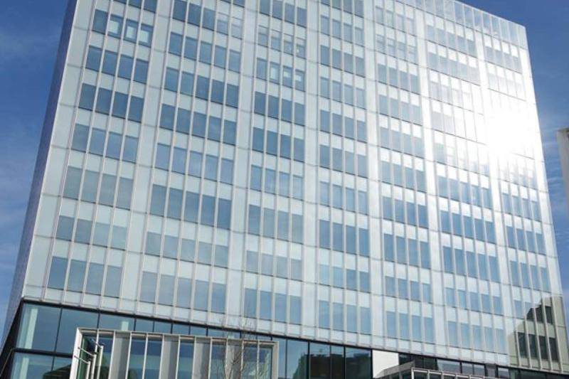 Das Gebäude ist in seiner ganzen Höhe zu sehen. Die 16 Geschossige Glasfassade glänzt in der Sonne. Die Fesnterelemnete sind schmal aber geschosshoch aufgeteilt. Die unteren vier Geschosse sind mit schwarzen Rahmen gebaut, darüber sind die Fesnterfassungen Alle weiß.