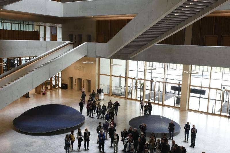 Das offene Foyer ist offen und sehr hell. Treppen erstrecken sich über die Stockwerke, jedoch quer durch das hohe Foyer und in unterschiedlichen Richtungen und Winkeln.