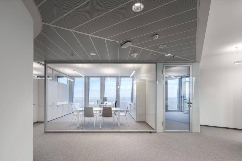 Pausenraum abgetrennt durch Glaswand. Alles in weiß und hellen grau Tönen. Im Hintergrund Ausblick durch die großen Fenster. Pausenraum abgetrennt durch Glaswand. Alles in weiß und hellen grau Tönen. Im Hintergrund Ausblick durch die großen Fenster.