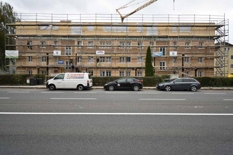 Blick über die Straße auf das Gebäude im Bauzustand. Um das Haus steht Gerüst. Im Hintergrund ist ein Kran zu sehen. Die Fassade ist während dem Bau braun zu erkennen.  Blick über die Straße auf das Gebäude im Bauzustand. Um das Haus steht Gerüst. Im Hintergrund ist ein Kran zu sehen. Die Fassade ist während dem Bau braun zu erkennen.