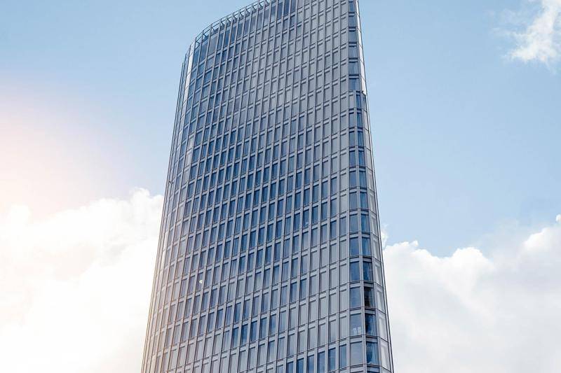 Das Hochhaus besteht aus einer einzigen Glashülle, die in Geschosshohe Fenster untreteilt ist. Das Glas schimmert dunkelblau durch die Sonne. Der Turm hat einen dreieckigen Grundriss und sie Ecken des Gebäudes sind mit unterschiedlichen radien abgerundet. Das Hochhaus besteht aus einer einzigen Glashülle, die in Geschosshohe Fenster untreteilt ist. Das Glas schimmert dunkelblau durch die Sonne. Der Turm hat einen dreieckigen Grundriss und sie Ecken des Gebäudes sind mit unterschiedlichen radien abgerundet.